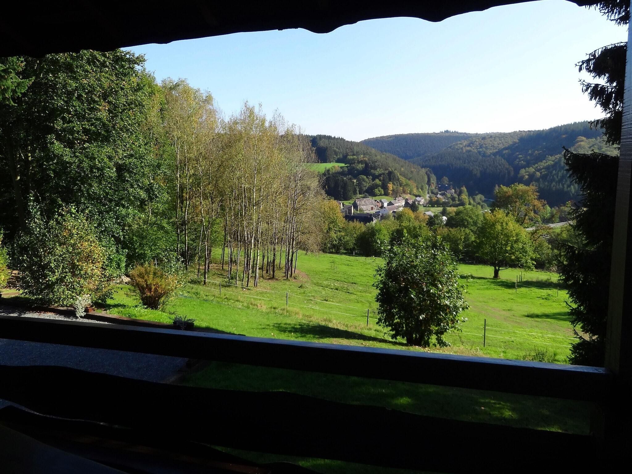 A view of a rural landscape with a house surrounded by trees and open fields.
