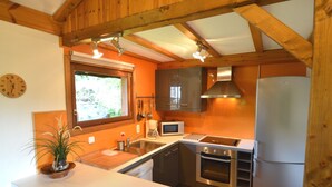 A kitchen with wooden beams, a sink, a microwave, an oven, and a refrigerator.