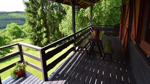 A wooden deck with a railing, a bench, and a potted plant.