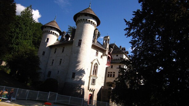 Un château doté d’une piscine, entouré d’arbres et d’une clôture blanche.