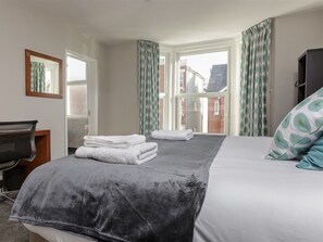 A hotel room with a bed, a desk, a chair, and a window with curtains. - Blue Star House (Portsmouth)
