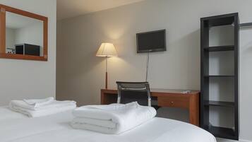 Ein Hotelzimmer mit Bett, Schreibtisch, Stuhl, Fernseher und Kleiderschrank.