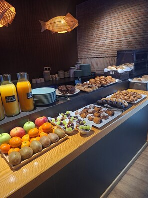 A breakfast buffet with fruits, pastries, and juice dispensers. - Hotel Oriente (Teruel)
