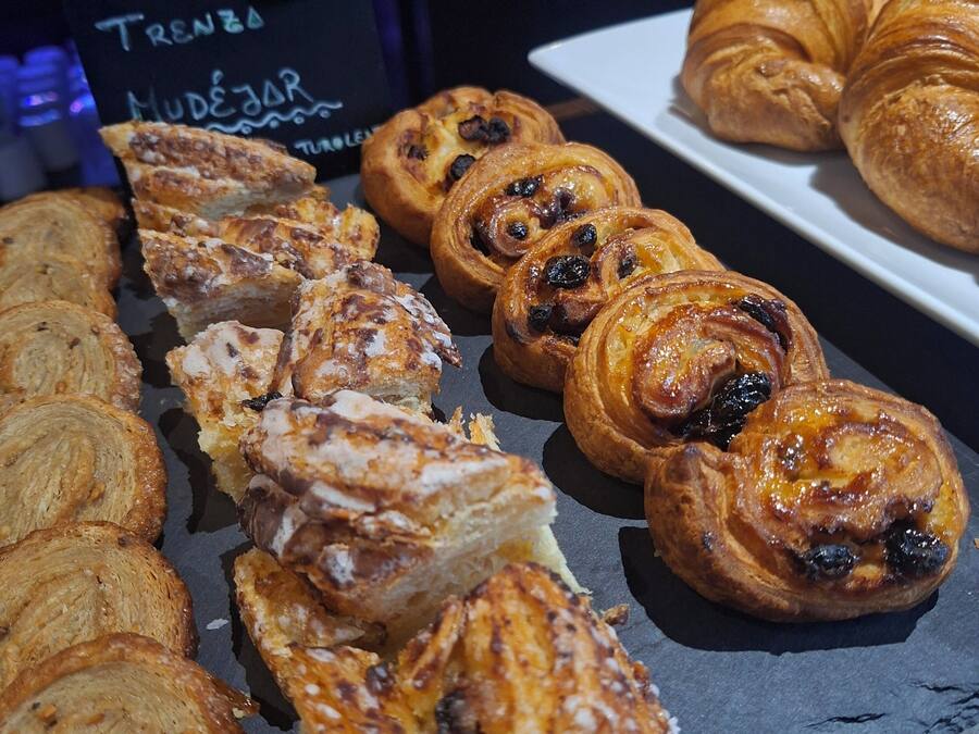 A display of various baked goods, including pastries and bread, arranged on a slate board.