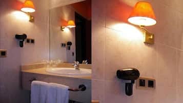 Une salle de bain équipée d’un lavabo, d’un miroir, d’un porte-serviettes et d’un sèche-cheveux fixé au mur.