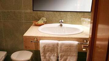 Un baño con lavamanos, espejo e inodoro.