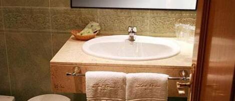 Un baño con lavamanos, espejo e inodoro.