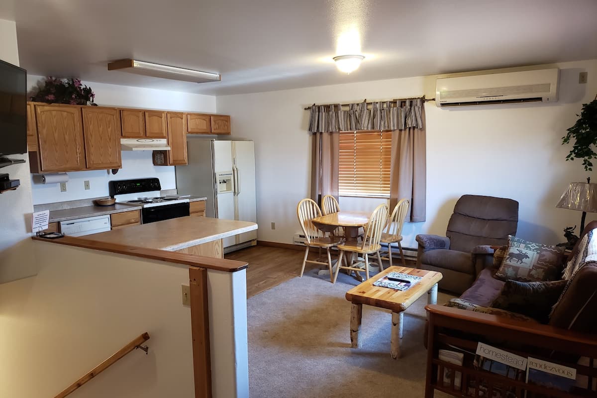 Un espacio habitable compacto con kitchenette, comedor y zona de estar.
