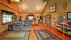A log cabin interior with a leather sofa, wooden shelves, and a chandelier. - Wolf Den Log Cabin Motel and RV Park (Etna)