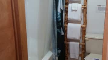 Une salle de bain avec des toilettes, un porte-serviettes en bois et un rideau de douche.