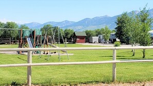 A campground with RVs, a playground, and a mountain backdrop. - Wolf Den Log Cabin Motel and RV Park (Etna)