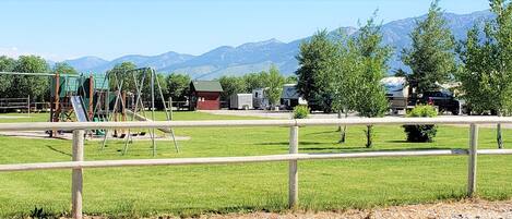 A campground with RVs, a playground, and a mountain backdrop.