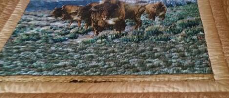 Un lit avec une peinture représentant des bisons sur une couverture à motifs.