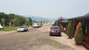 A gravel road leading to a lodge with multiple cars parked. - Wolf Den Log Cabin Motel and RV Park (Etna)