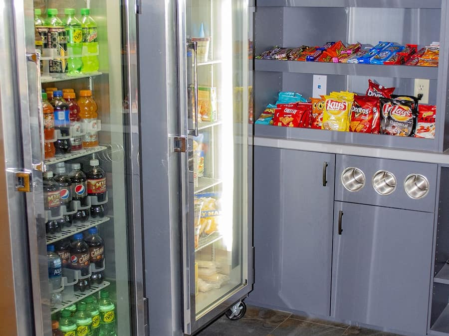 A vending machine area with a refrigerator stocked with beverages and snacks.