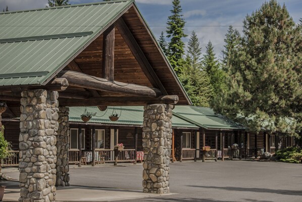 A lodge with stone pillars, green metal roofs, and wooden beams.