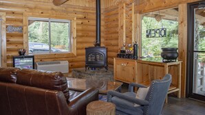 A cabin interior with a stone fireplace, leather sofa, and a wooden dining table. - Bonners Ferry Log Inn (Bonners Ferry)