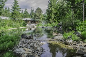Ein rustikales Blockhaus mit Teich, umgeben von dichtem Wald.