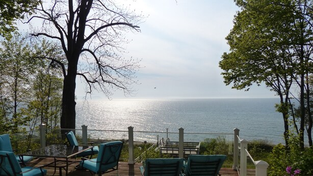 A wooden deck with outdoor seating, overlooking a body of water. - Good Harbor Bay Estate, Lake Michigan (Lake Leelanau)