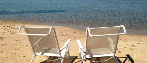 En privat strand, hvidt sand, liggestole, parasoller