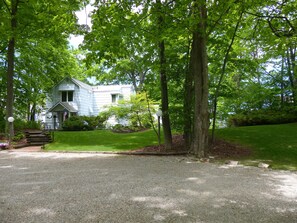 A house with a front porch, surrounded by a well-maintained lawn and trees.