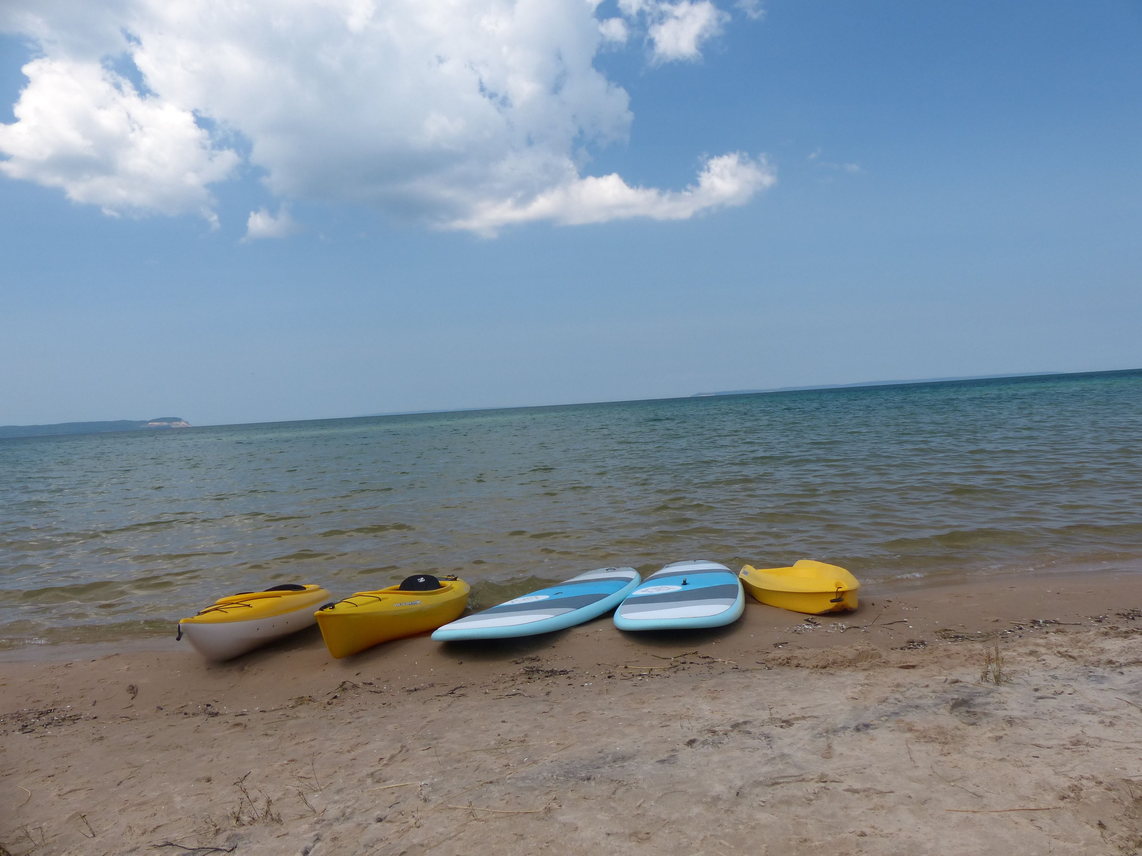A beach with kayaks lined up on the sand.