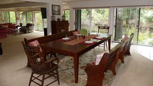 A spacious dining area with a large wooden table set for four, surrounded by wooden chairs. - The Weaver House (Glen Arbor)