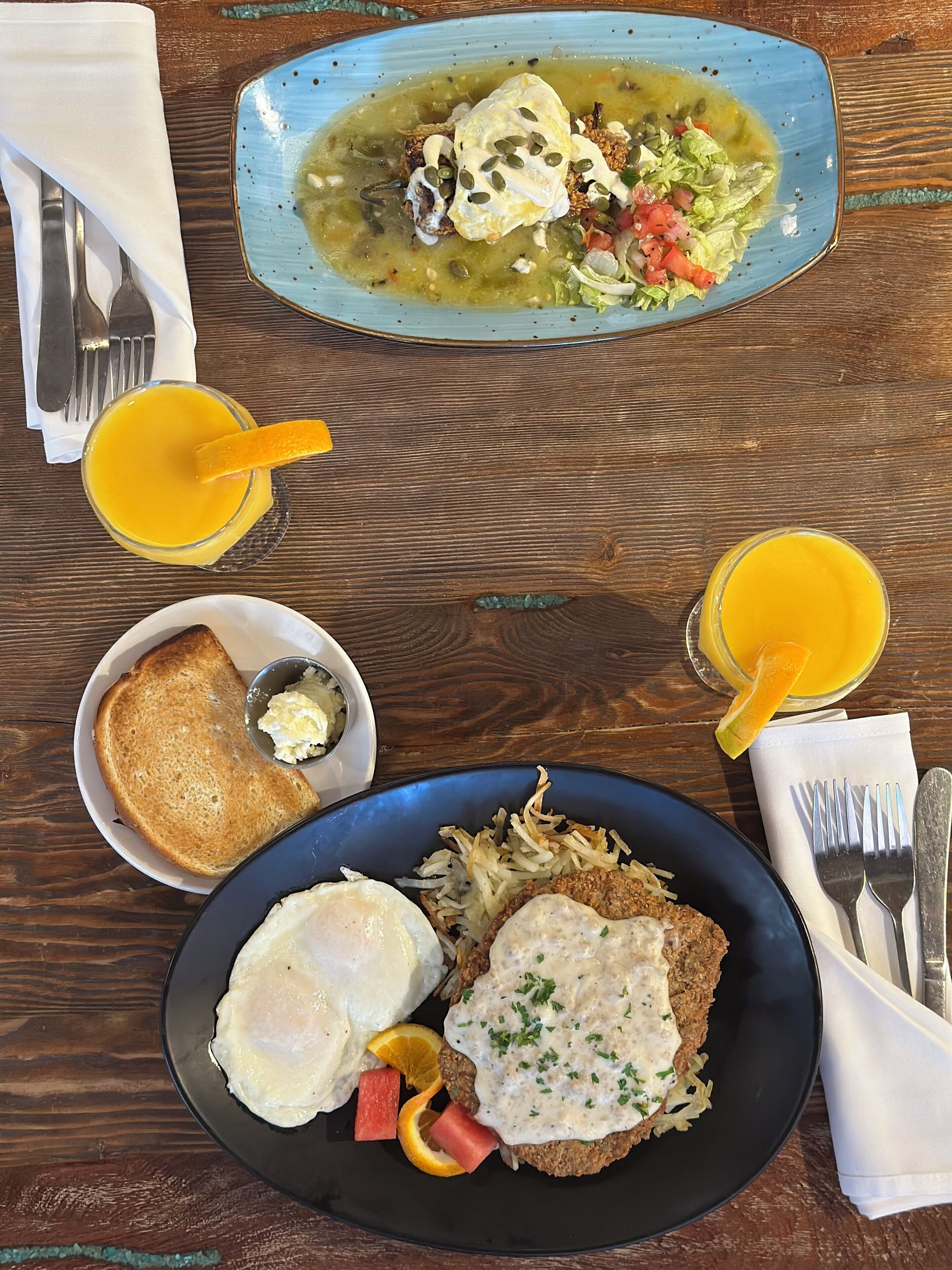 A breakfast plate with eggs, hash browns, toast, and a side of green sauce.