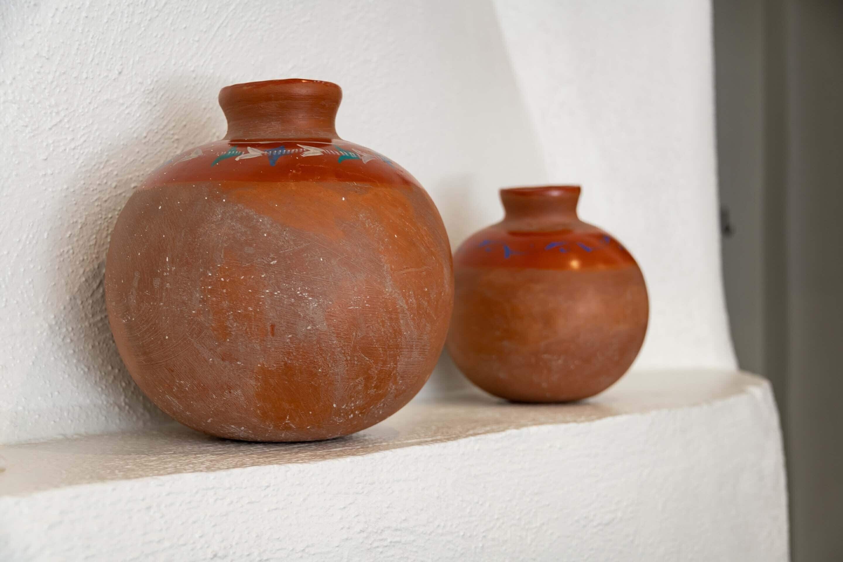 Two ceramic vases on a white shelf against a white wall.