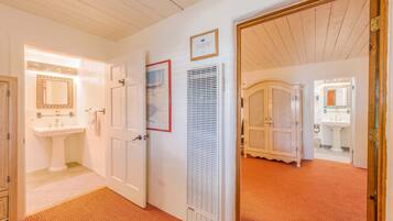 A hallway with a white door leading to a bathroom, a framed picture on the wall, and a white radiator.