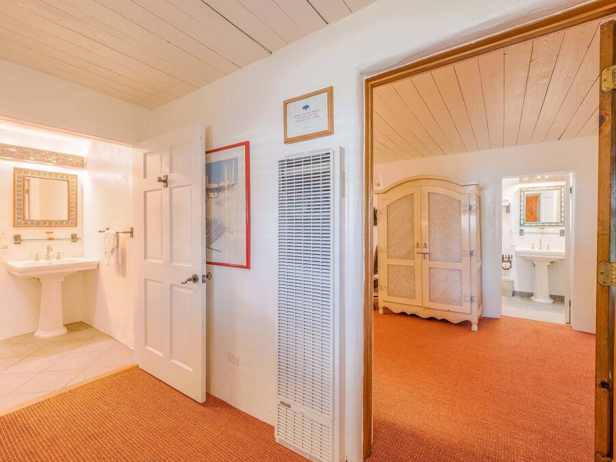A hallway with a white door leading to a bathroom, a framed picture on the wall, and a white radiator.