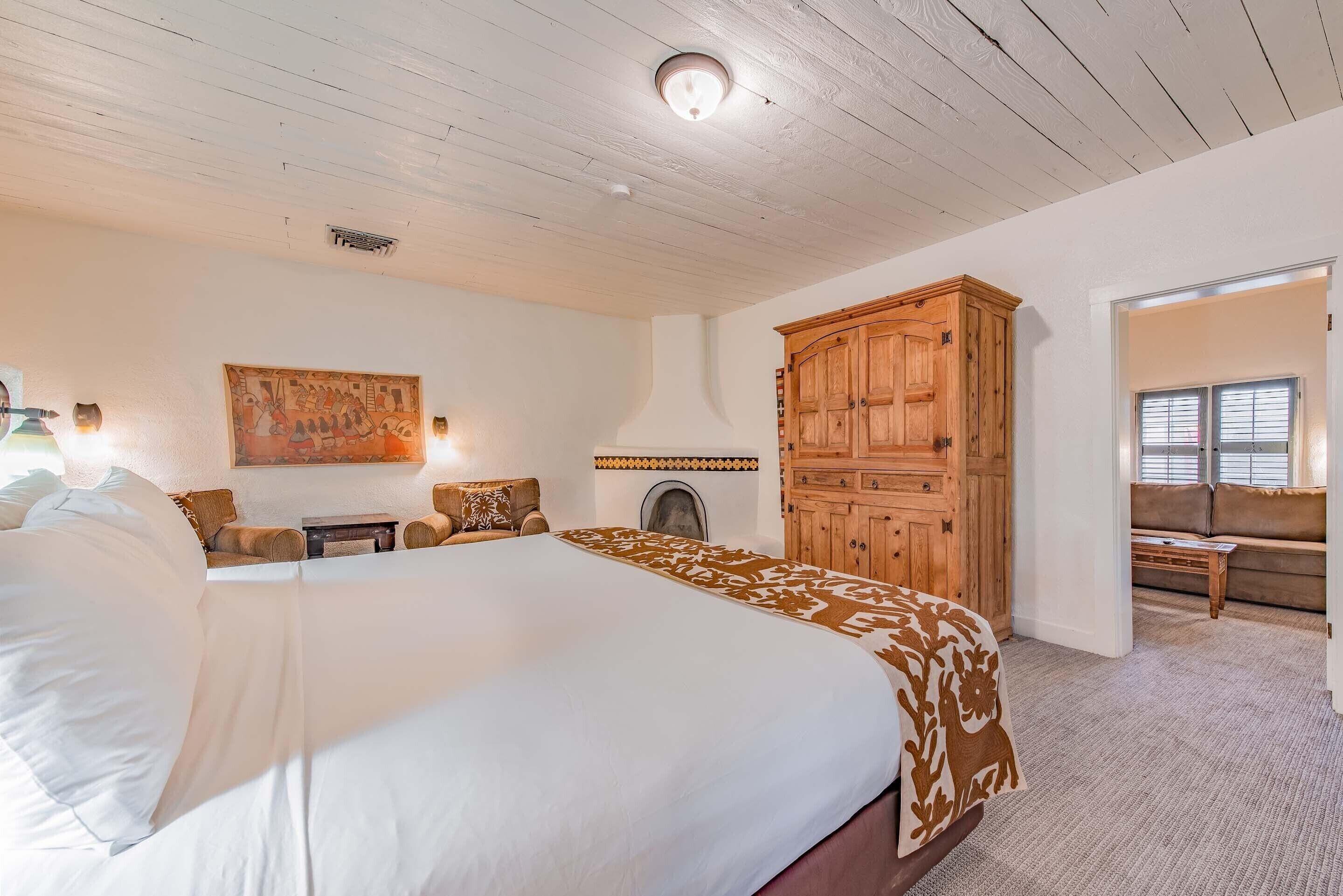 Un dormitorio con una cama grande, un armario de madera, una chimenea y un cuadro en la pared.