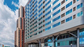 A modern hotel with a prominent red and grey facade, large windows, and a clear sky.