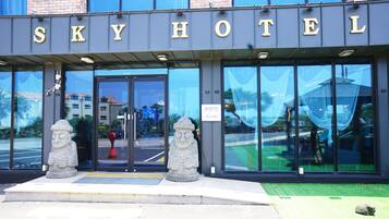 The exterior of the Sky Hotel with large glass doors and a stone statue in front.