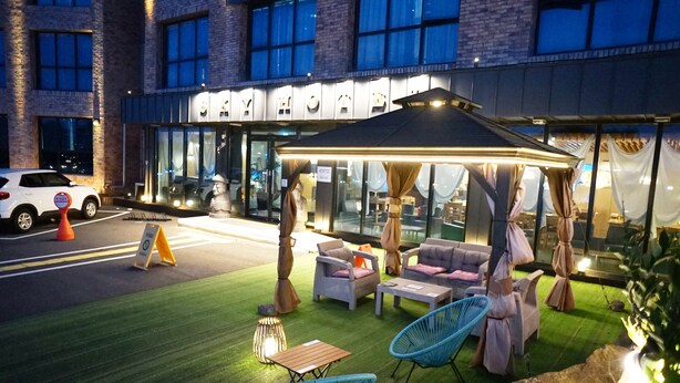 An outdoor seating area with a canopy, chairs, and tables. - Sky Hotel (Jeju City)