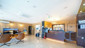 A hotel reception area with a TV, seating, a reception desk, and a "Staff Only" door. - Sky Hotel (Jeju City)
