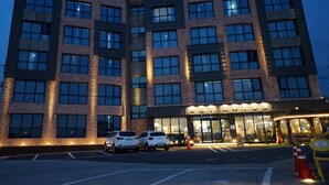 A multi-story hotel with a modern architectural design, featuring a prominent entrance with glass doors and a well-lit facade. - Sky Hotel (Jeju City)