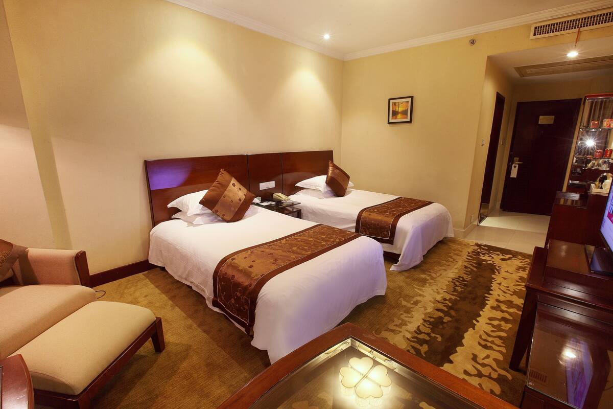 Ein Hotelzimmer mit zwei Betten, einer Couch, einem Fernseher und Teppichboden.