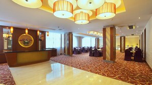 A spacious hotel lobby with a reception desk, multiple seating areas, and a patterned carpet.
