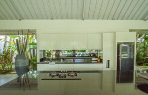 A modern kitchen with a gas stove, white cabinets, and a large vase of plants.