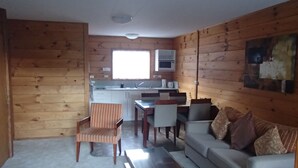 Ein kompakter Wohnbereich mit Küchenzeile, einem Essbereich und einer Sitzecke mit Sofa und Sesseln.