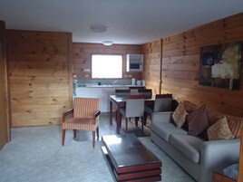 Um espaço compacto com cozinha compacta, área de refeições e sala de estar com sofá e poltronas.