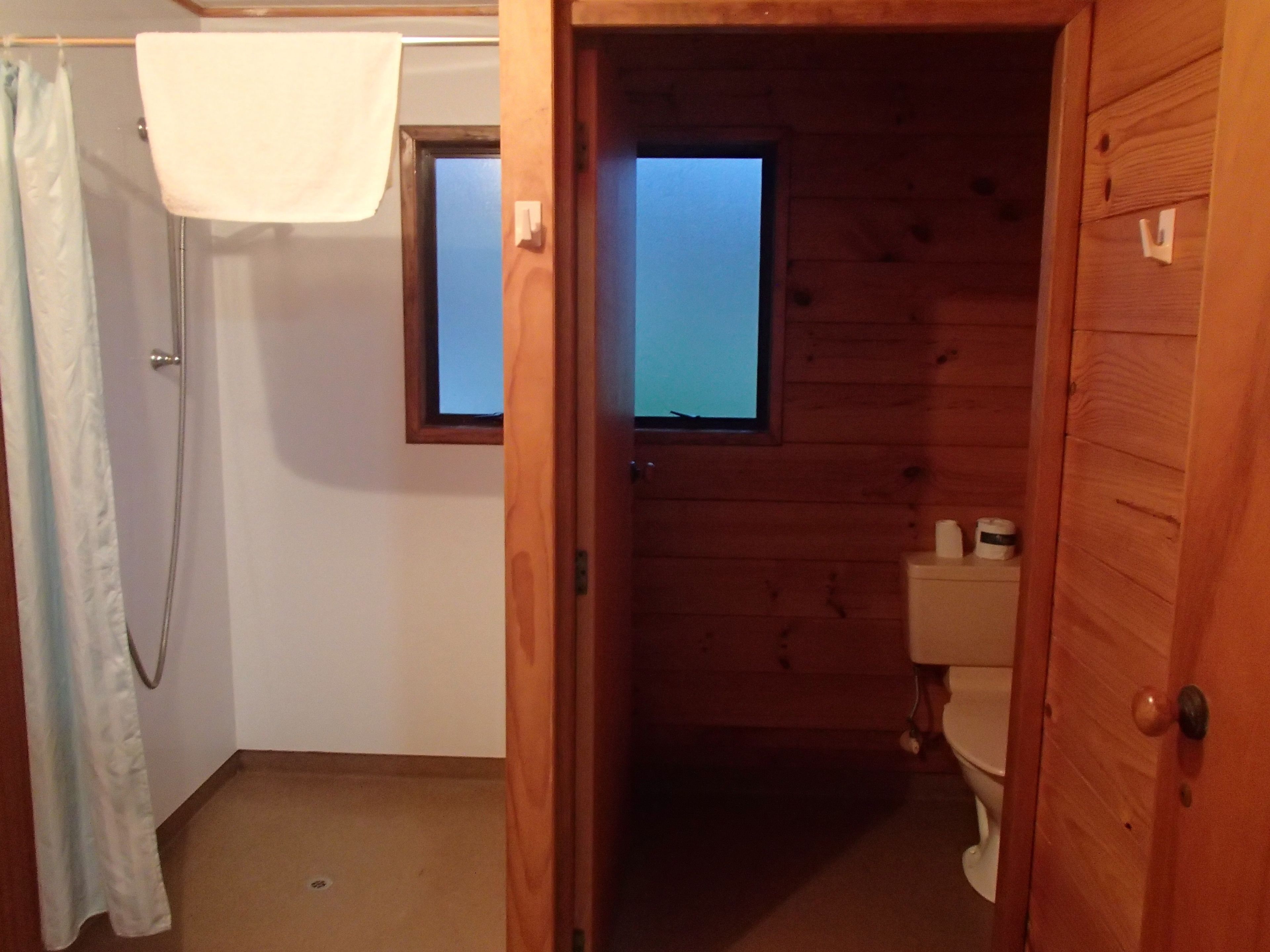 Une salle de bain en bois avec un rideau de douche, une fenêtre et des toilettes.