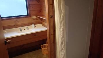 A wooden bathroom with a white sink, a window, and a shower curtain.