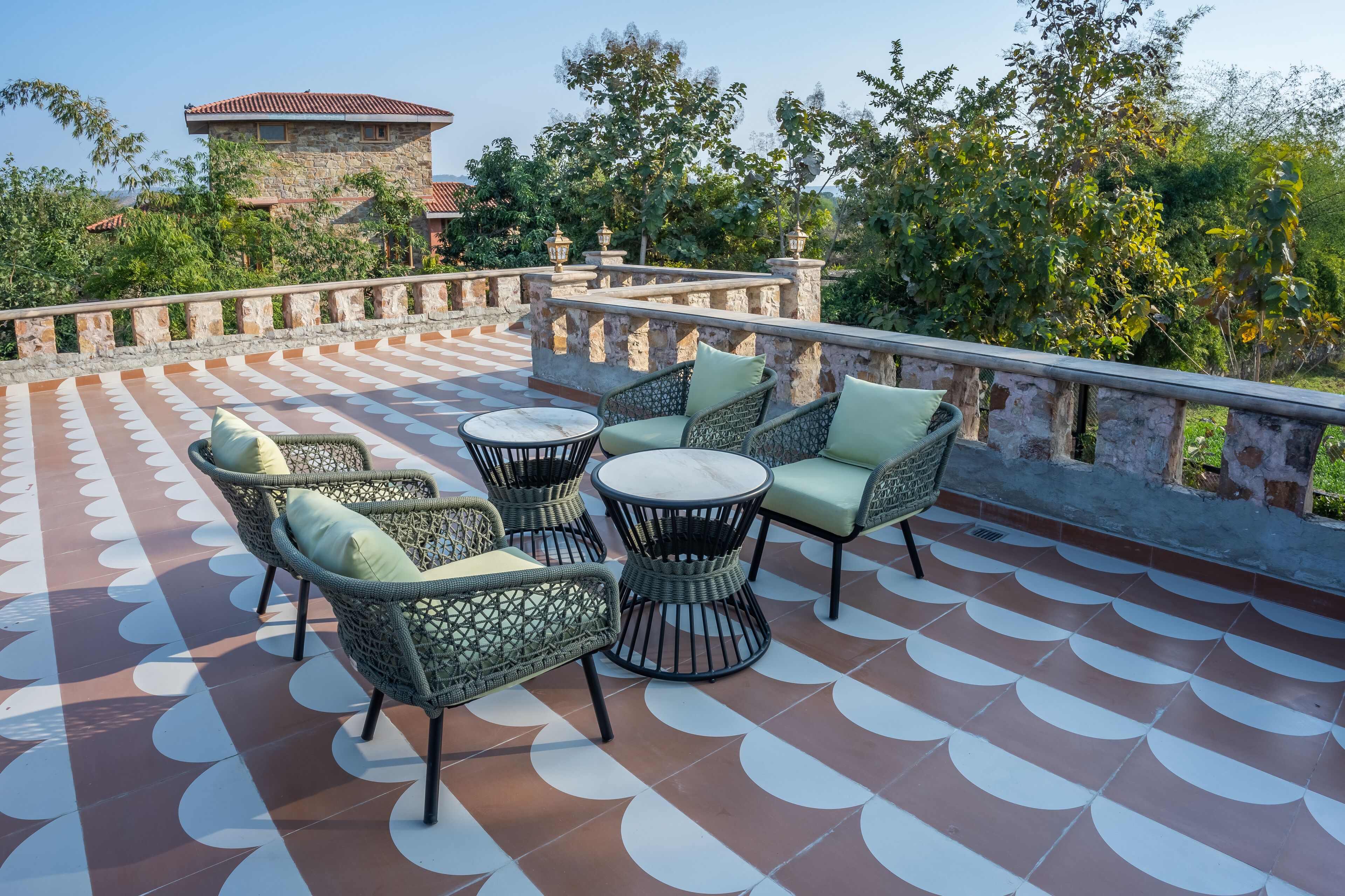 Une terrasse dotée de meubles en osier, d’un sol à motifs et d’un mur en pierre.