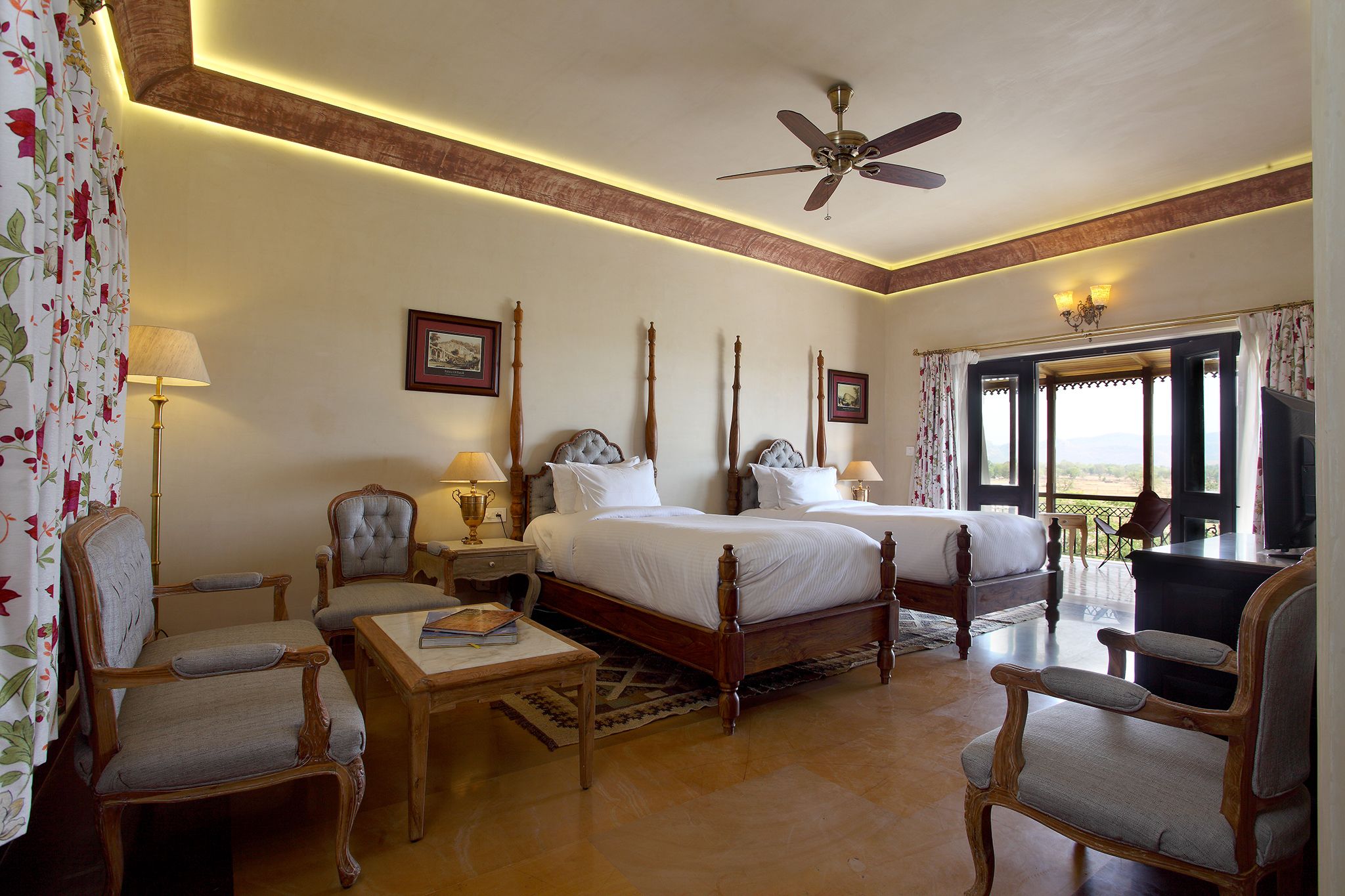 A hotel room with a large bed, two bedside tables, a ceiling fan, and a balcony with a view.