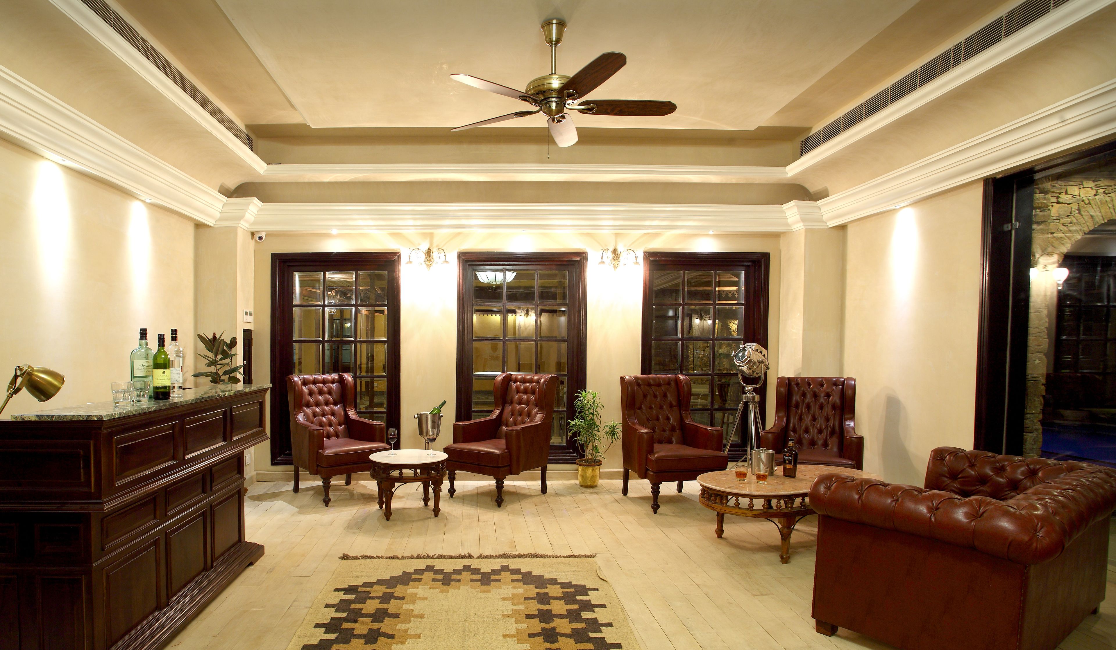 A spacious living room with a ceiling fan, leather armchairs, a coffee table, and a large window.