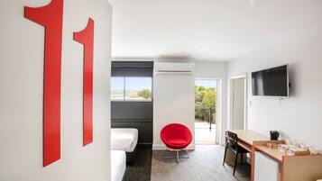 Une chambre d’hôtel moderne avec un grand numéro « 11 » sur le mur, un lit, une chaise rouge, un bureau et un téléviseur.