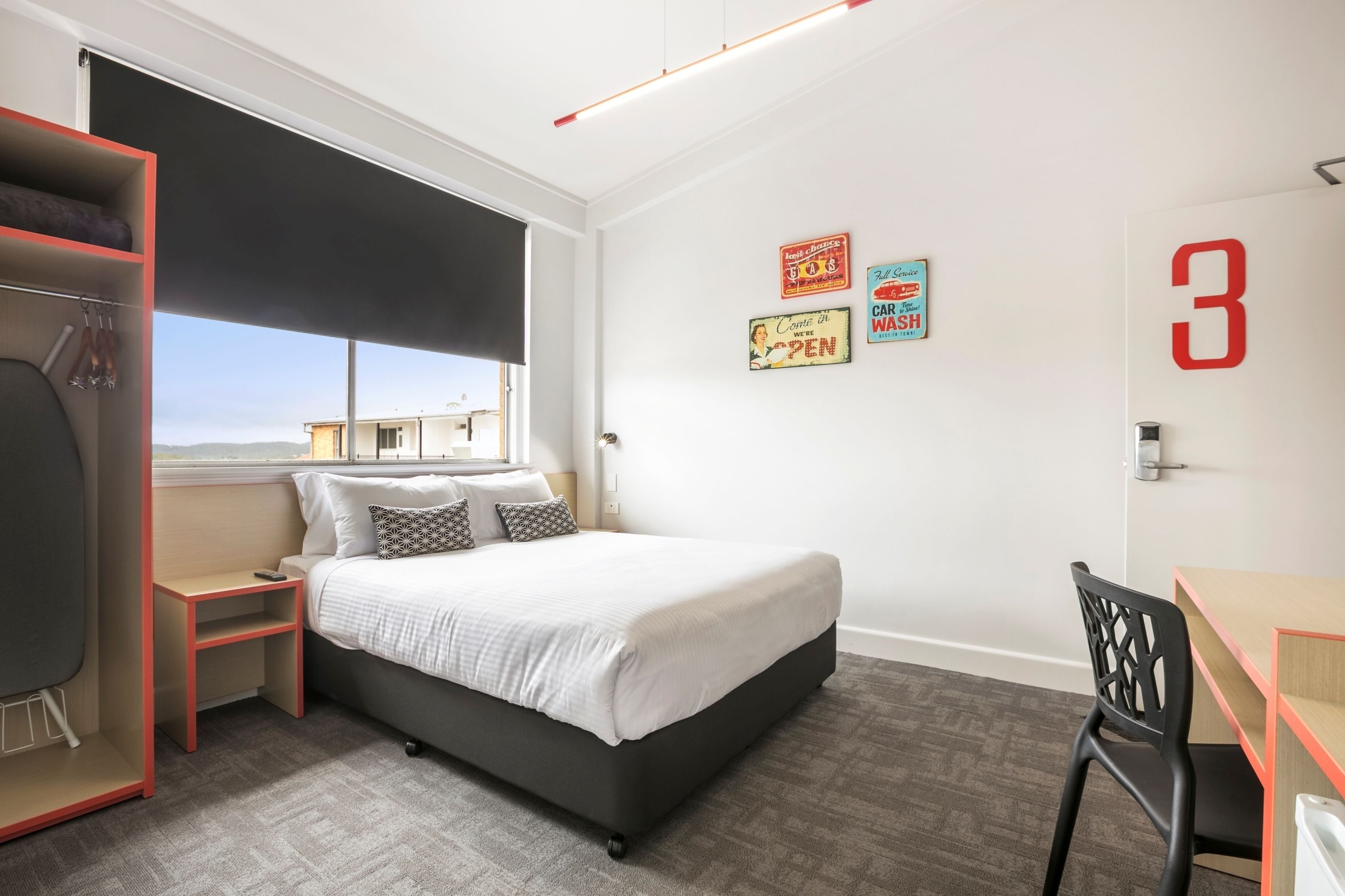 A modern bedroom with a bed, a desk, and a wardrobe. There are wall decorations and a number '3' on the wall.