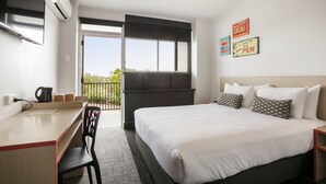 Una habitación de hotel con cama, escritorio, silla y balcón con vistas.